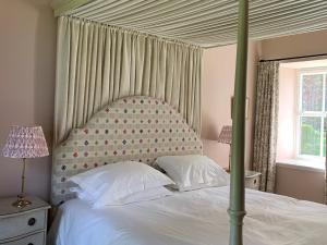 ein Schlafzimmer mit einem Himmelbett mit weißer Bettwäsche und Kissen in der Unterkunft 1 Bed in Forres 78430 in Forres