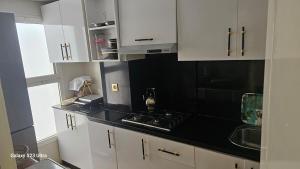 a kitchen with white cabinets and a black counter top at Appartement de plage front de mer in Tamaris