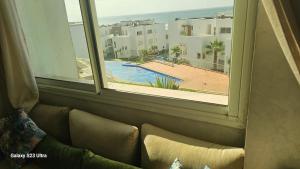 a living room with a window looking out at a pool at Appartement de plage front de mer in Tamaris