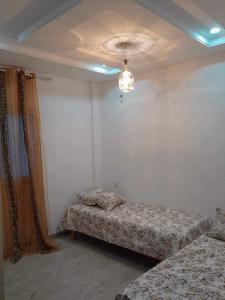 a room with two beds and a ceiling with a chandelier at appartement ostanding in Kelibia