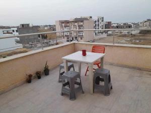 a white table and two stools on a roof at appartement ostanding in Kelibia