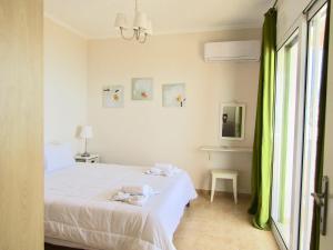 a bedroom with a bed with white sheets and green curtains at Barbati Beach Apartments in Barbati