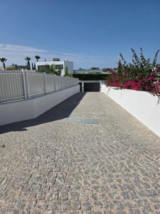 a brick walkway with a white fence and pink flowers at Villa Paraiso in Alcantarilha +36 photos