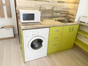 eine Küche mit Waschmaschine und Mikrowelle in der Unterkunft Studio Green Rublyovka in Warna