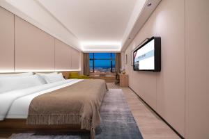 Una habitación de hotel con una cama y un televisor de pantalla plana. en Yunduo Hotel Puning International Commodity City Branch, en Puning