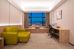 Una habitación con una silla amarilla y un escritorio y una ventana. en Yunduo Hotel Puning International Commodity City Branch, en Puning