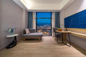 Una sala de estar con una silla y una ventana grande. en Yunduo Hotel Puning International Commodity City Branch, en Puning