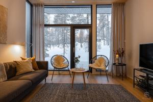 Una sala de estar con un sofá y sillas frente a una ventana. en Villa Suunnikas by Hilla Villas, en Ylläsjärvi