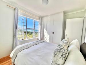 a bedroom with a bed and a large window at Fijnbosch Villa at Claptons in Jeffreys Bay