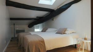 a bedroom with two beds and a ceiling with beams at Maison de village - Font Bénite in Saint-André-la-Côte