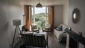 a living room with a couch and chairs and a window at Maison de village - Font Bénite in Saint-André-la-Côte