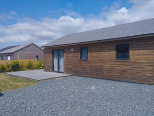 a home with a wooden wall and a driveway at Chalet - Cottage de Lesconil in Plobannalec-Lesconil