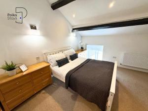 a bedroom with a large bed and a wooden dresser at No 2 PolkaStays Ivy Farm Rosewood Cottage in Plumpton