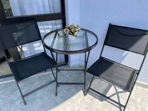 a glass table with two chairs and a vase of flowers at Хотел Калитеа in Pomorie