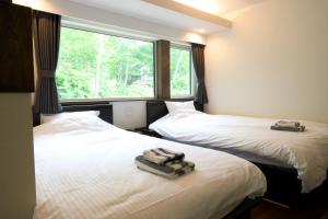 two beds with towels on top of them in a room at Uli Villa Onsen in Niseko