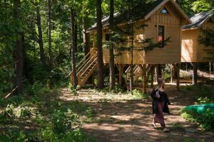 a woman walking in front of a tree house at Bakasana in Ruciane-Nida
