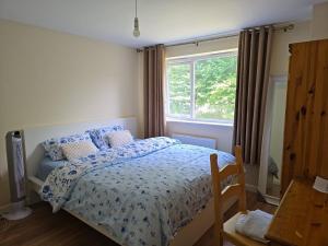 a bedroom with a bed with a blue comforter and a window at Highly Comfortable Home in Hatfield