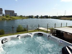a bath tub sitting next to a body of water at Still Waters - Luxury Lakeside Retreat with Hot Tub in Warmwell