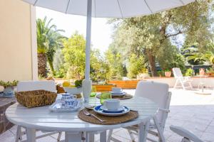 a white table with chairs and an umbrella at Villa Oceri Gioiosa Marea in Gioiosa Marea