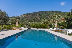 a pool with chairs and umbrellas and a mountain at Villa Oceri Gioiosa Marea in Gioiosa Marea