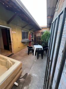 eine Terrasse mit einem weißen Tisch und schwarzen Stühlen in der Unterkunft Aluga fácil Caldas Bangalô in Caldas Novas