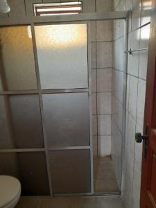 a shower with a glass door in a bathroom at Apartamento a 300m do Centro e próximo a universidade federal in Diamantina