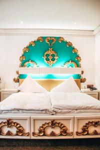 a bedroom with a bed with a blue and gold headboard at Hotel Saalbacher Hof in Saalbach-Hinterglemm