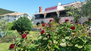 un edificio con un jardín con rosas rojas en Hotel Zlatni Lav, en Martinšćica