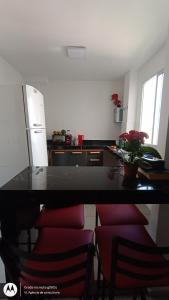 a kitchen with a counter with red chairs and a refrigerator at Apartamento inteiro in Aparecida de Goiania