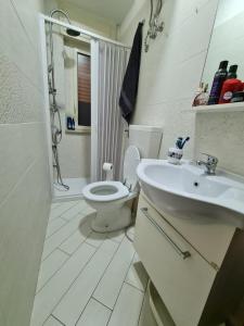 a white bathroom with a toilet and a sink at Apartman SOFIA - close to the railway station in Scalea