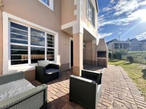a patio with a couch and chairs and a building at Fijnbosch Villa at Claptons in Jeffreys Bay