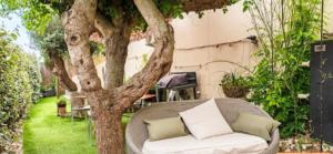 a white couch sitting next to a tree in a yard at T2 entre Mer et Montagnes in Porto-Vecchio