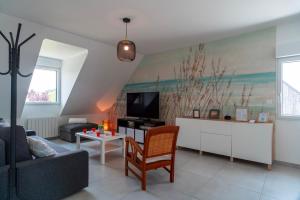 Una sala de estar con un sofá y un televisor. en Le Haut du Nelud - Appt dans maison avec jardin, en Locmariaquer
