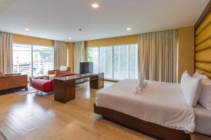 a bedroom with a bed and a desk with a television at The Kris Resort Hotel in Patong Beach +43 photos