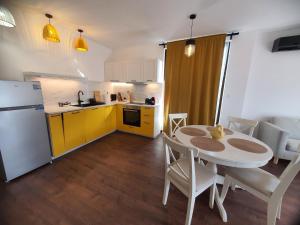a kitchen and dining room with a table and yellow cabinets at Вила Винсент - Villa Vincent in Lozenets +15 photos