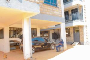 a man sitting in a chair in front of a car at Eldoret 3bedroom Apartment in Eldoret