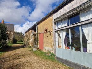 un vecchio edificio con una porta rossa e una finestra di La Petite Foucaudière, 10 couchages a Mansigné Altre 3 foto