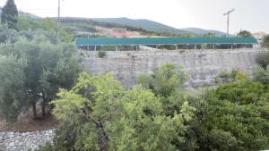 a retaining wall with trees and a blue roof at Ponti Beach Hotel in Vasiliki