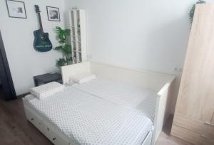 拉拉古纳Natur Vida Home Tenerife的一间白色的卧室，墙上挂着一张床和一把吉他