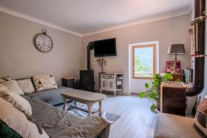 a living room with a couch and a clock on the wall at Appart Authentique et Confortable in Valderoure