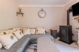 a living room with a couch and a clock on the wall at Appart Authentique et Confortable in Valderoure +23 photos