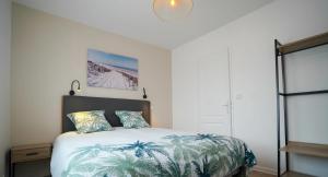 una camera da letto con un letto con un piumone di palma di lueur de mer a Meschers-sur-Gironde