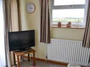a living room with a flat screen tv and a window at The Cockles in Ulgham