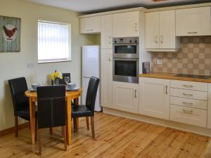 a kitchen with a table and chairs and a refrigerator at The Cockles in Ulgham