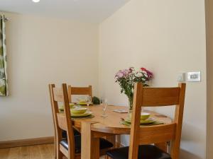 una mesa de madera con sillas y un jarrón de flores en River Cottage, en Llangunllo