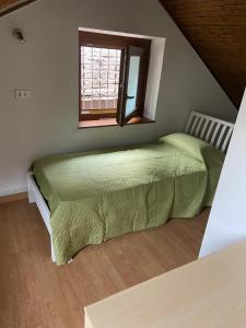 1 dormitorio con cama verde y ventana en Ca d'la Netta, en Malesco