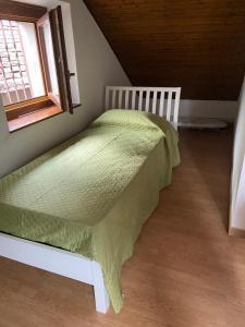 1 dormitorio con 1 cama con edredón verde y ventana en Ca d'la Netta, en Malesco 1 foto más