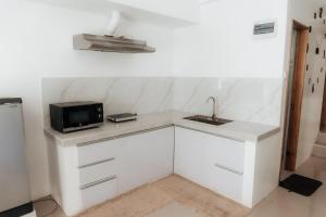 a white kitchen with a sink and a microwave at MG Transient House in Baguio