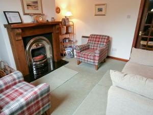 ein Wohnzimmer mit zwei Stühlen und einem Kamin in der Unterkunft 15 Cairnbaan Cottage in Cairnbaan