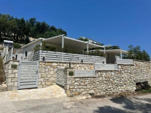 a house on a stone wall with a fence at Rouli's Houses by All About Paxos in Oziás